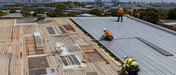 Roofers replacing deteriorated metal roof sheets on a Sydney commercial building
